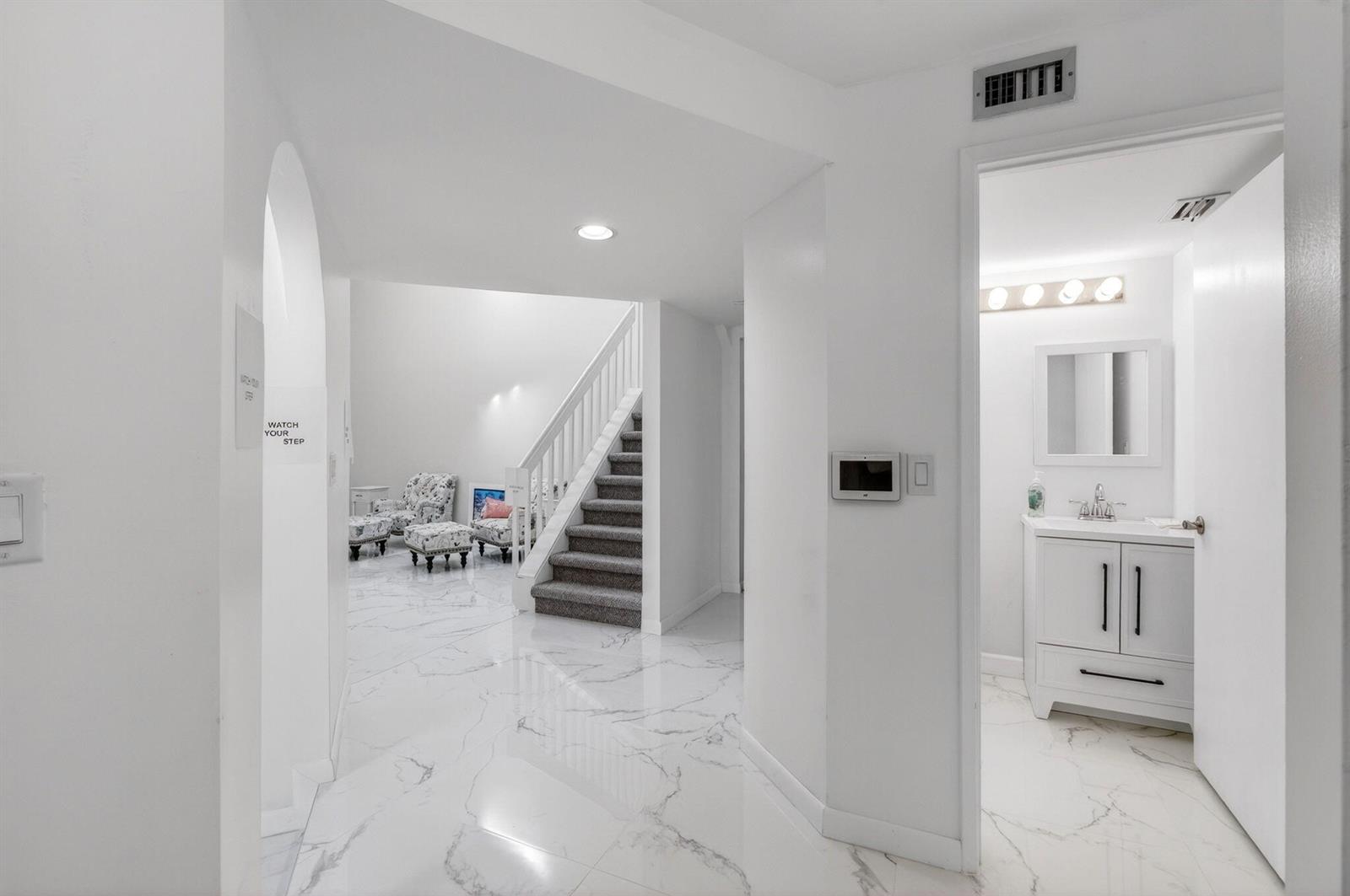A bright entryway features white marble floors, a staircase with gray carpet, and a bathroom — 7865 La Mirada Drive, Boca Raton FL 33433, BOCA RATON, FL