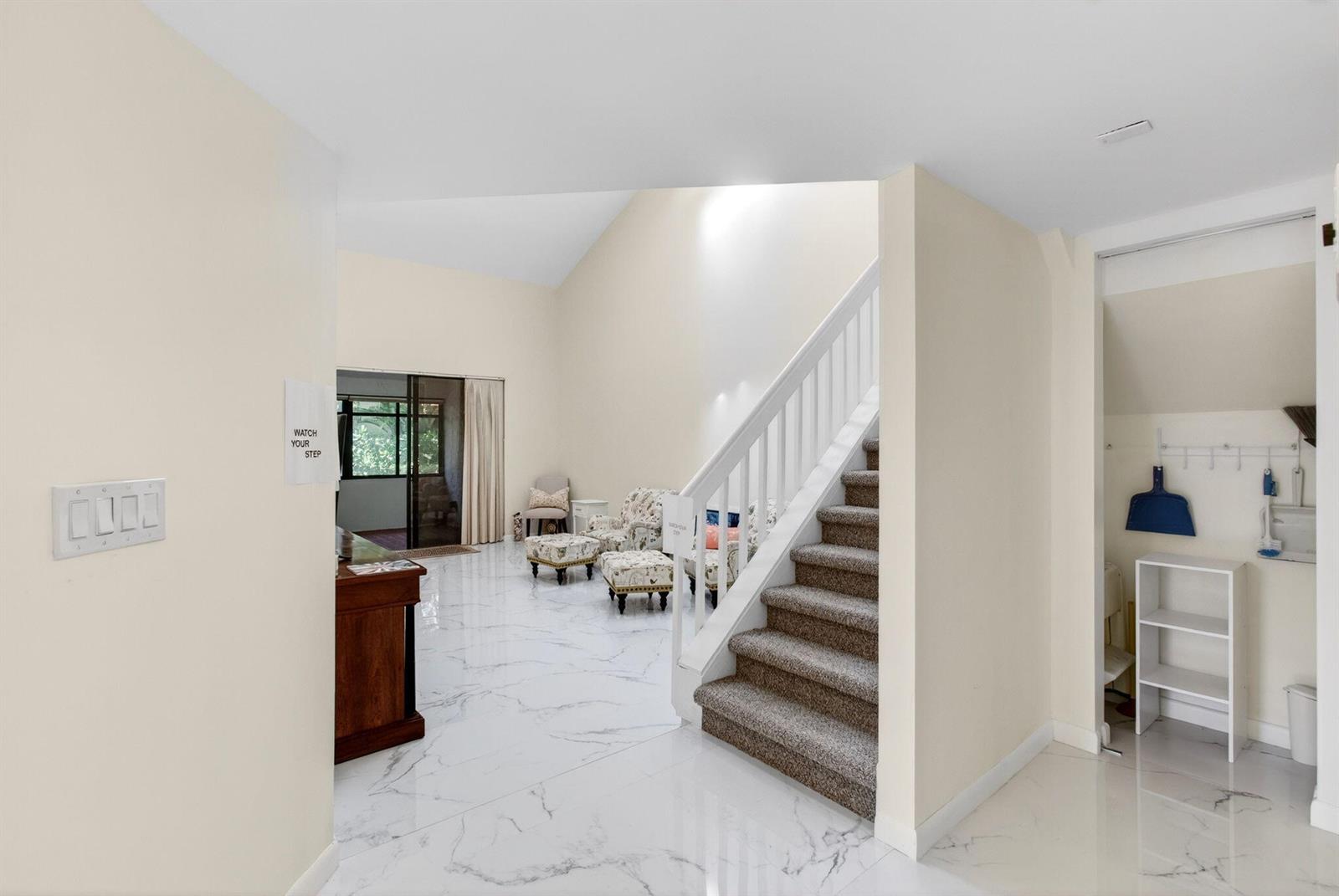 A bright living area features white marble floors, a carpeted staircase, and a sliding glass door — 7865 La Mirada Drive, Boca Raton FL 33433, BOCA RATON, FL