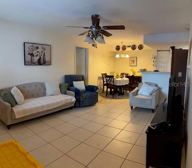 A living room with tile floors, a sofa, an armchair, and an adjacent dining area — 3036 PARKWAY BOULEVARD UNIT 205, KISSIMMEE, FL