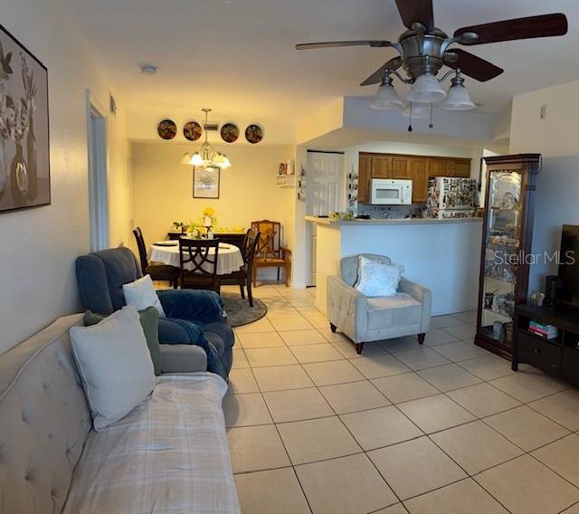 A living room and dining area with tile flooring, a ceiling fan, and kitchen access — 3036 PARKWAY BOULEVARD UNIT 205, KISSIMMEE, FL