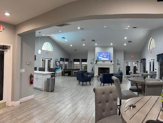A spacious community clubhouse features a fireplace, lounge seating, and a kitchen area with tile flooring — 3036 PARKWAY BOULEVARD UNIT 205, KISSIMMEE, FL