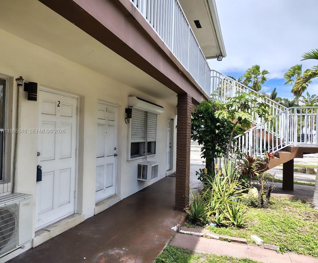 The exterior of a two-story building features a ground-level walkway with two white doors — 1816 Mckinley St # 2, Hollywood FL 33020, HOLLYWOOD, FL