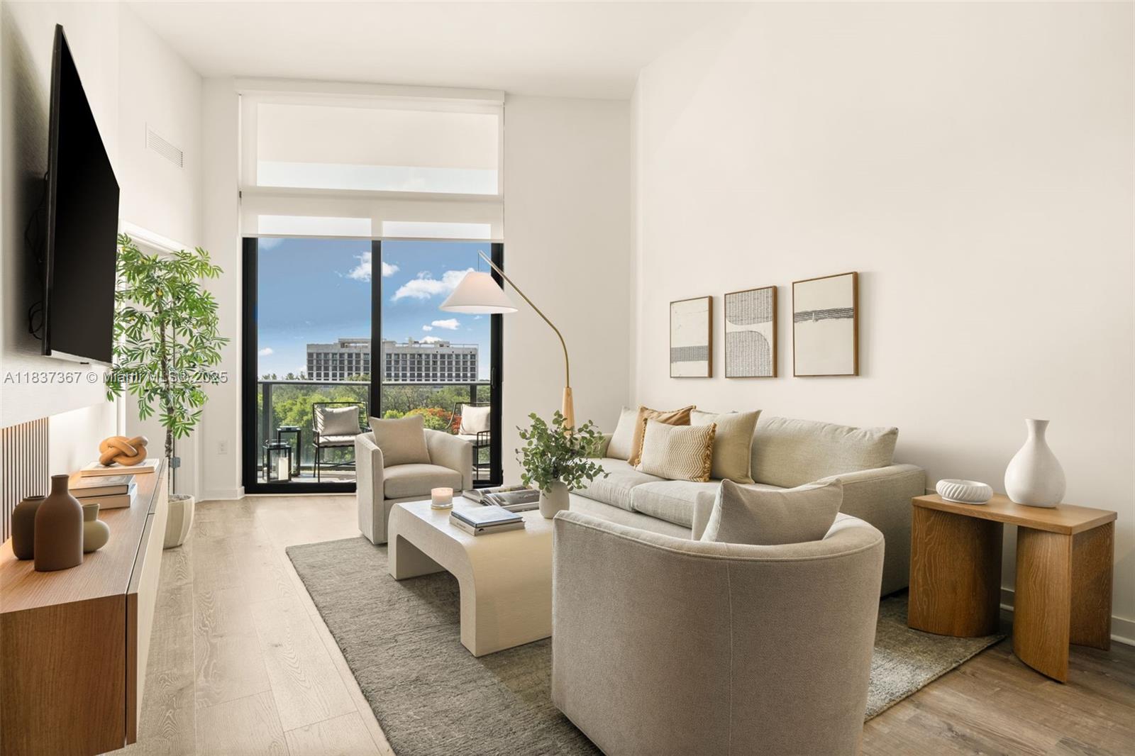 A modern living room features a sofa, armchairs, coffee table, and a balcony with views — 501 NE 31st St # 410, Miami FL 33137, MIAMI, FL