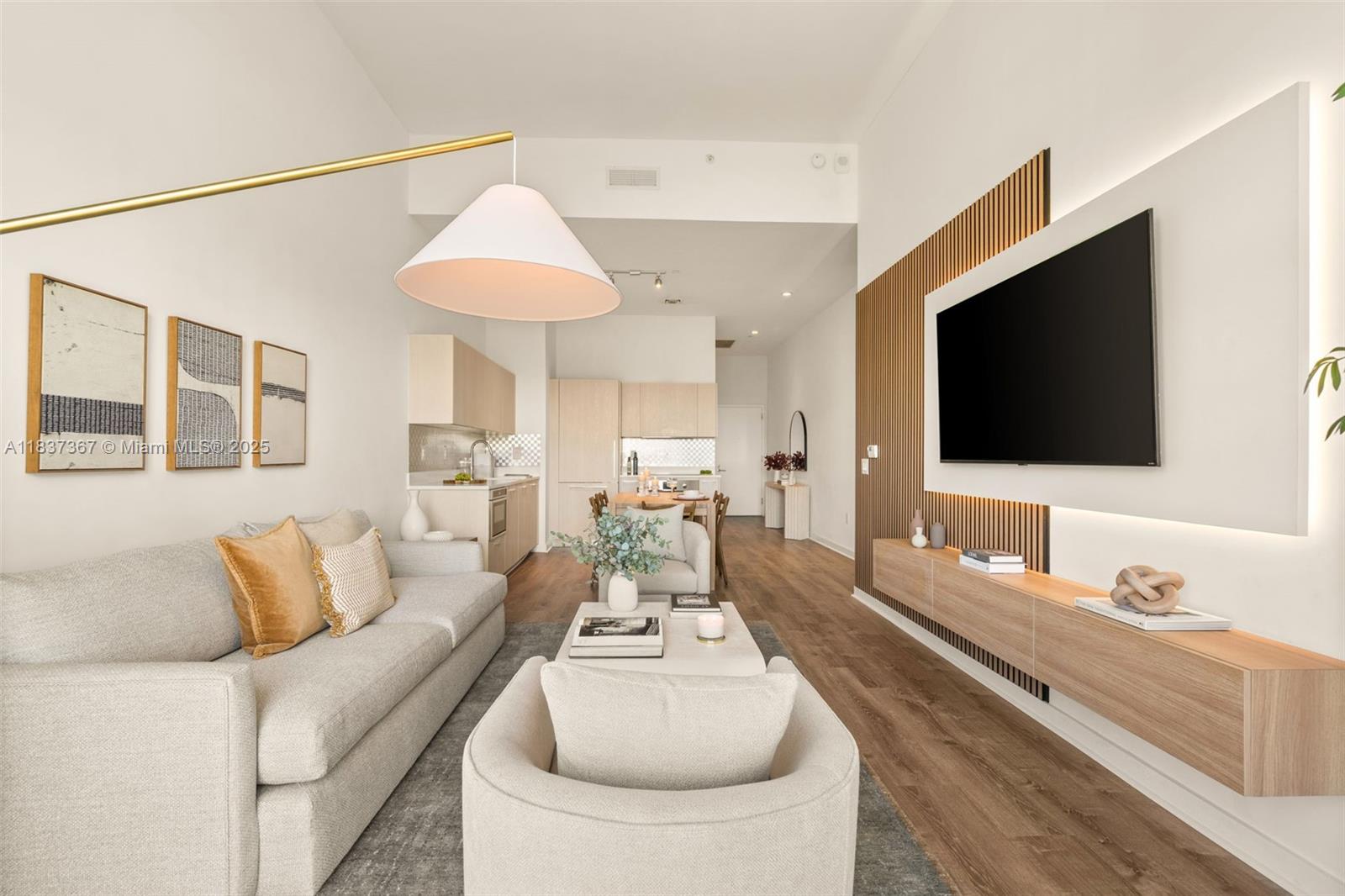 A modern living room features a wall-mounted television, wood slat paneling, and an open kitchen — 501 NE 31st St # 410, Miami FL 33137, MIAMI, FL