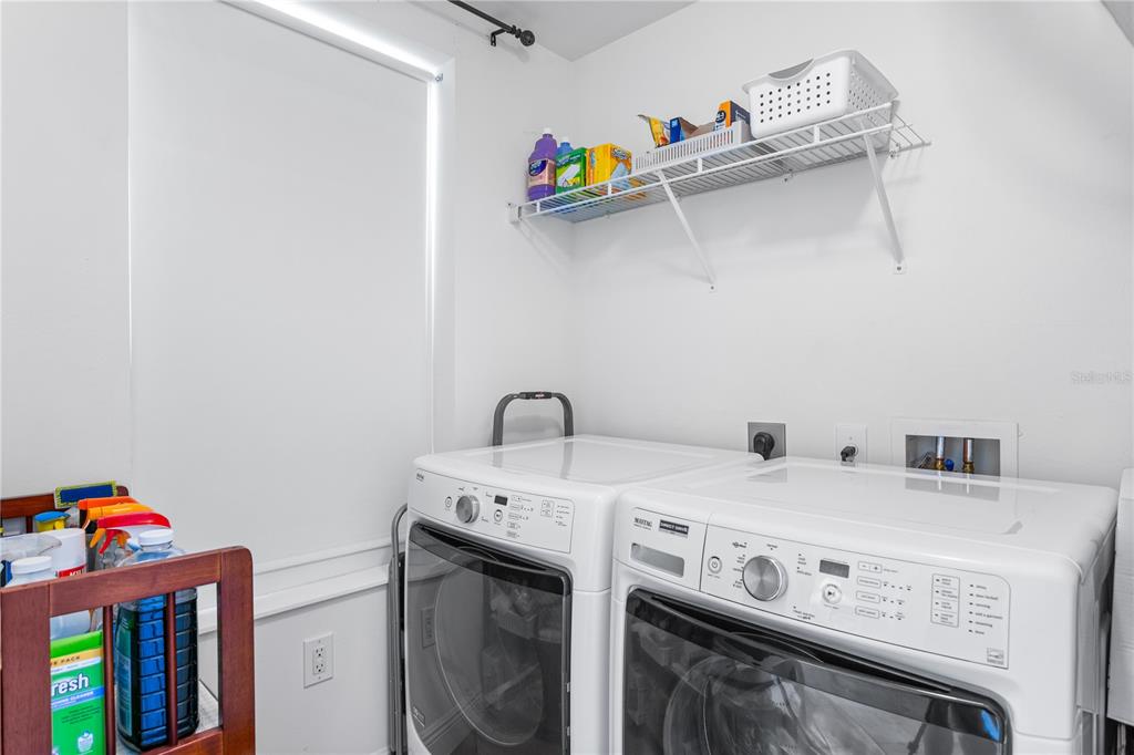 A laundry room featuring a white washer and dryer, a wire shelf, and cleaning supplies — 2743 1ST STREET UNIT 406, FORT MYERS, FL