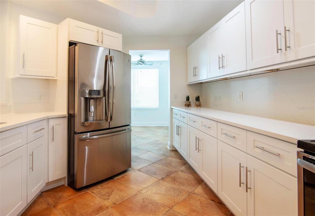 A kitchen features white cabinets, stainless steel appliances, white countertops, and brown tile flooring — 2743 1ST STREET UNIT 406, FORT MYERS, FL