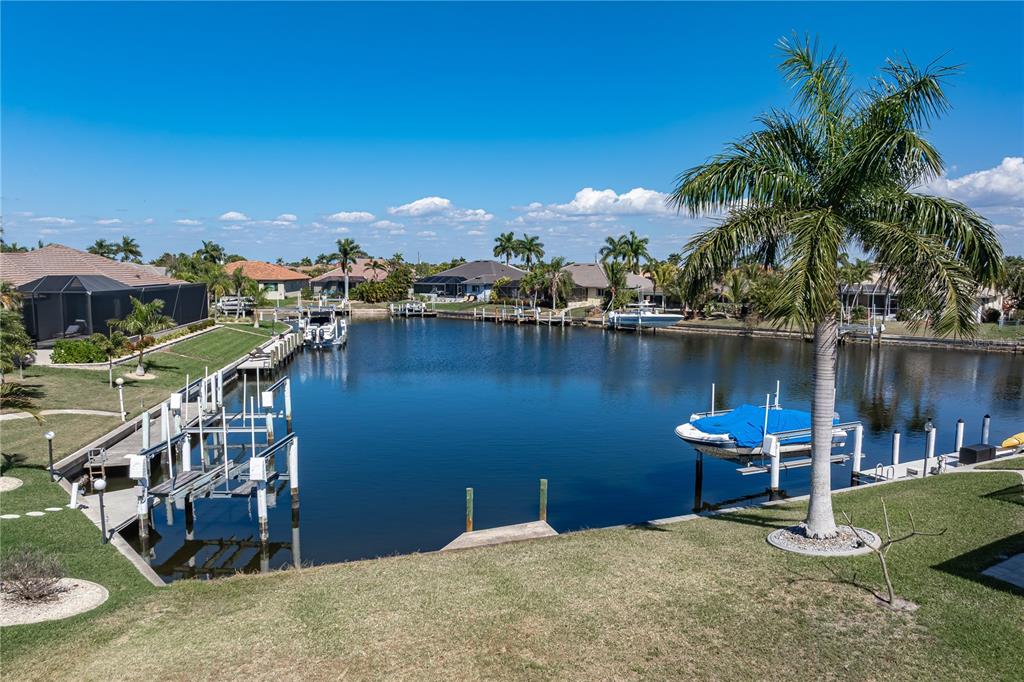 A residential backyard features a lawn, a boat dock, and a canal with boats — 5045 SAN MASSIMO DRIVE, PUNTA GORDA, FL