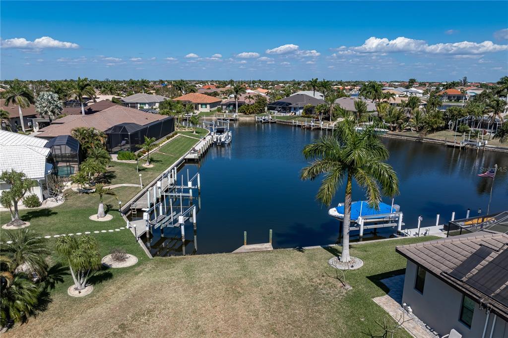 An aerial view shows a residential canal with private docks, palm trees, and surrounding houses — 5045 SAN MASSIMO DRIVE, PUNTA GORDA, FL