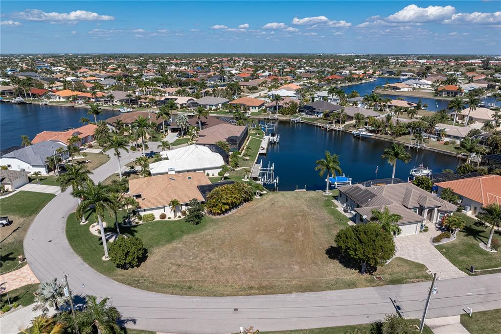 An aerial view shows a vacant waterfront residential lot situated between two existing houses — 5045 SAN MASSIMO DRIVE, PUNTA GORDA, FL