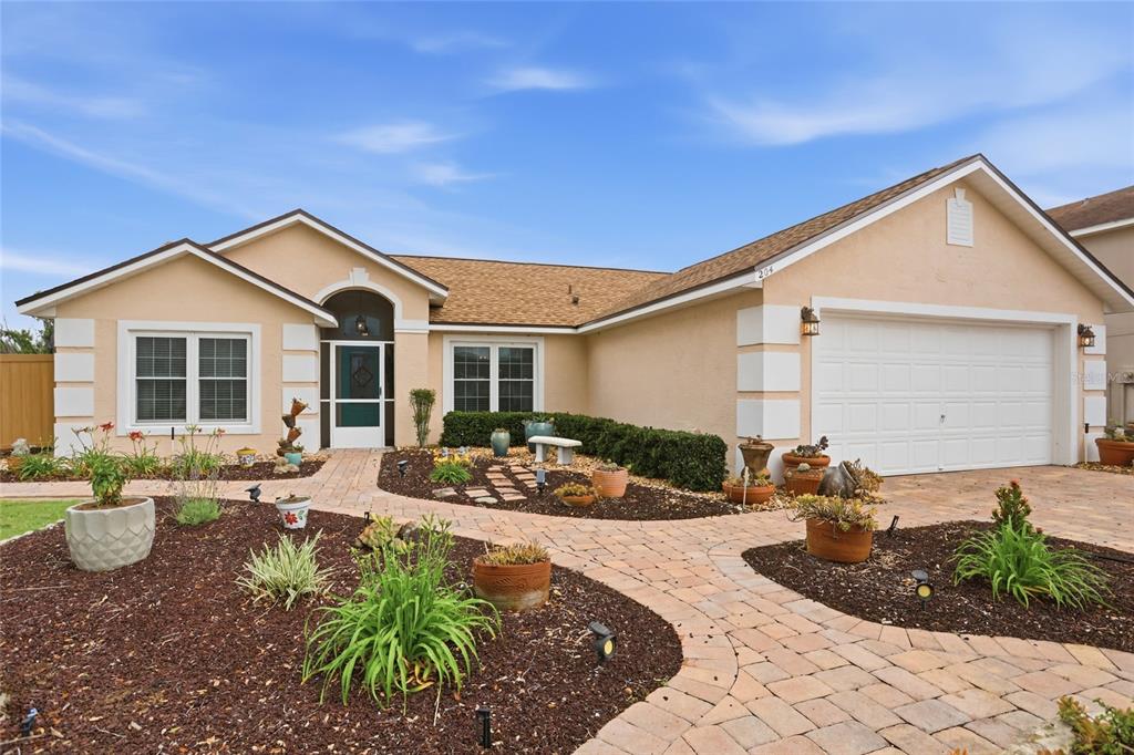 A single-story house with a beige stucco exterior, a paver walkway, and a two-car garage — 204 GREENWICH STREET, DAVENPORT, FL