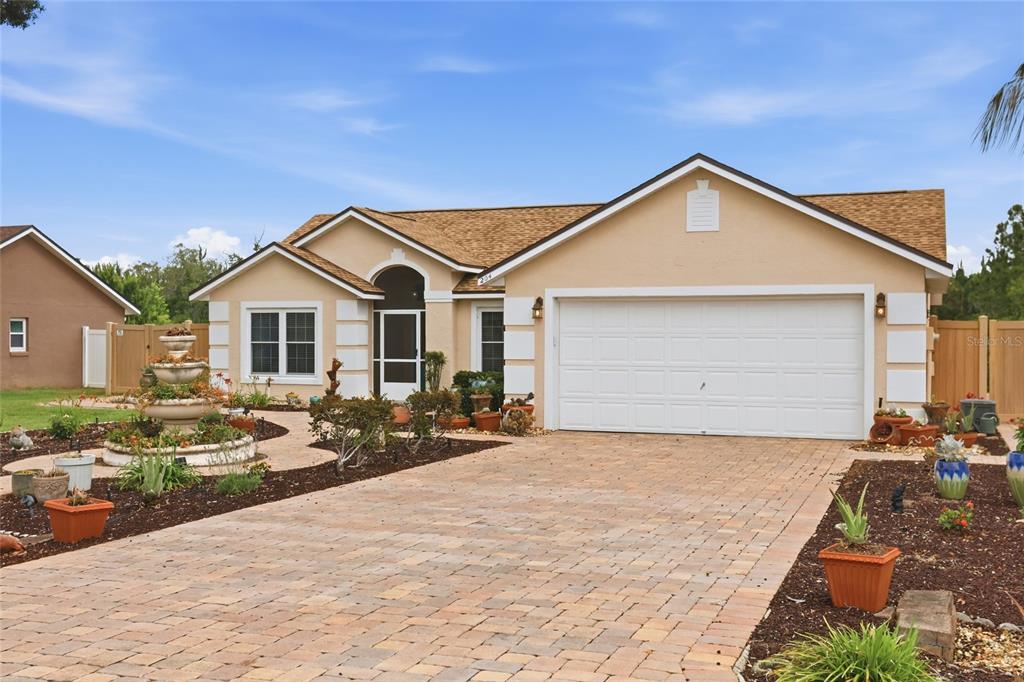 A single-story house with a tan exterior, a two-car garage, and a paved driveway — 204 GREENWICH STREET, DAVENPORT, FL
