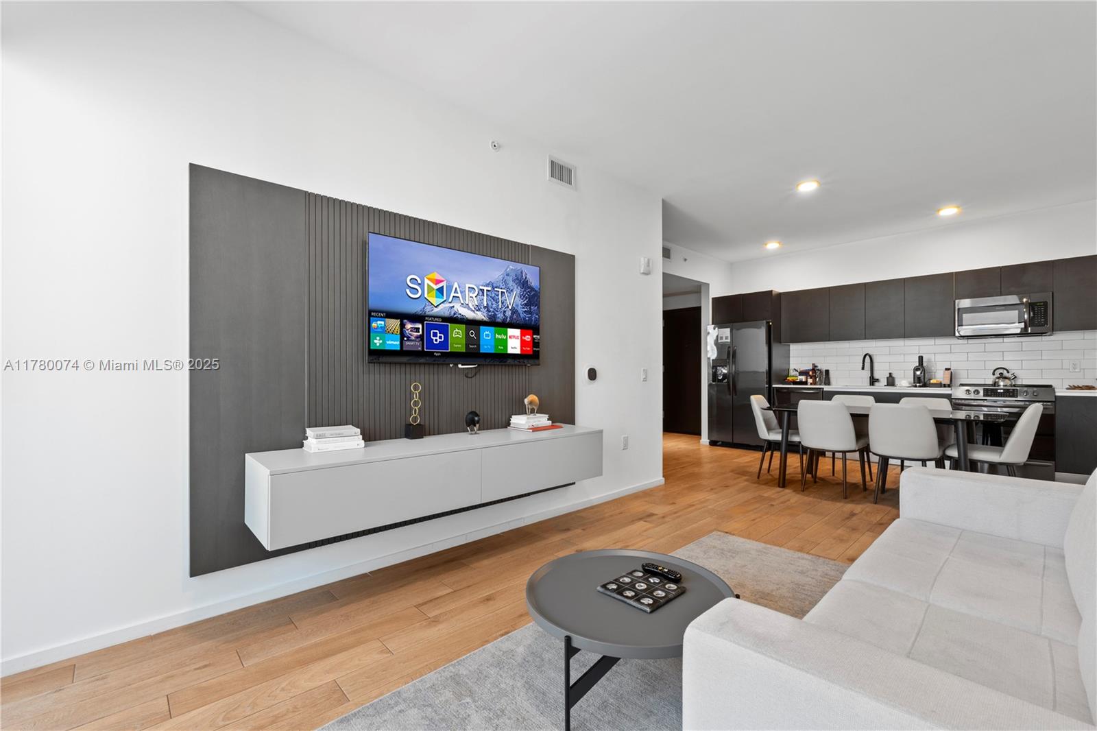 A modern living room features a wall-mounted television, floating console, and an open kitchen — 398 NE 5th St # 2119, Miami FL 33132, MIAMI, FL