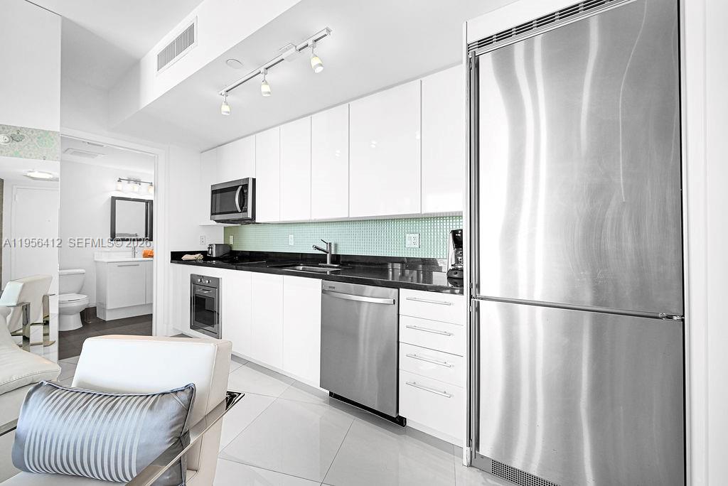 A modern kitchen features white cabinets, stainless steel appliances, and a black countertop — 92 SW 3rd St # 4806, Miami FL 33130, MIAMI, FL