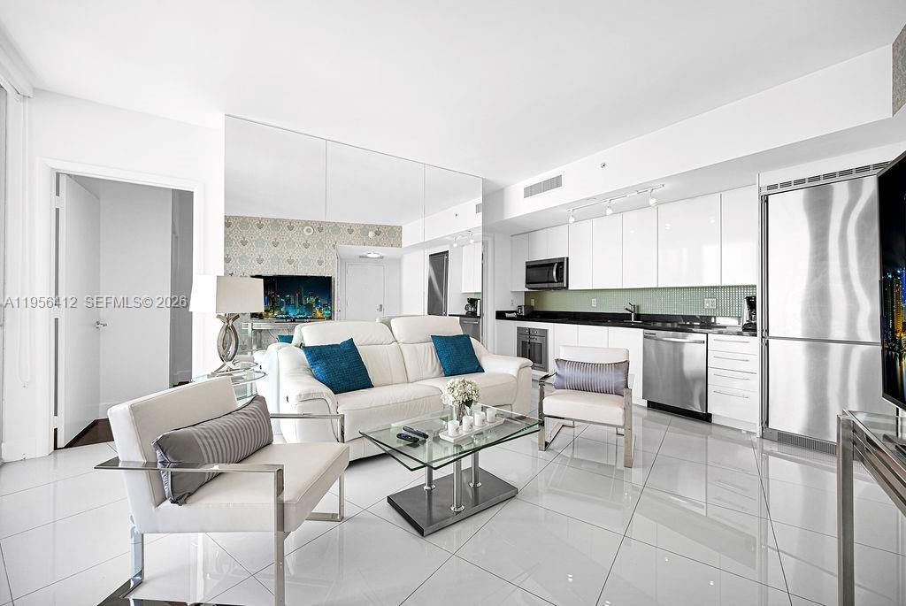 A modern living room features white tile floors, a white sofa, and an open kitchen — 92 SW 3rd St # 4806, Miami FL 33130, MIAMI, FL