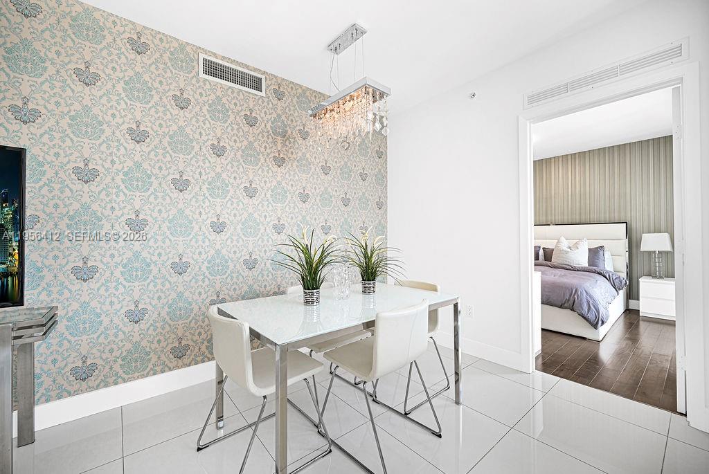A dining area features patterned wallpaper, a glass table, white chairs, and a crystal chandelier — 92 SW 3rd St # 4806, Miami FL 33130, MIAMI, FL