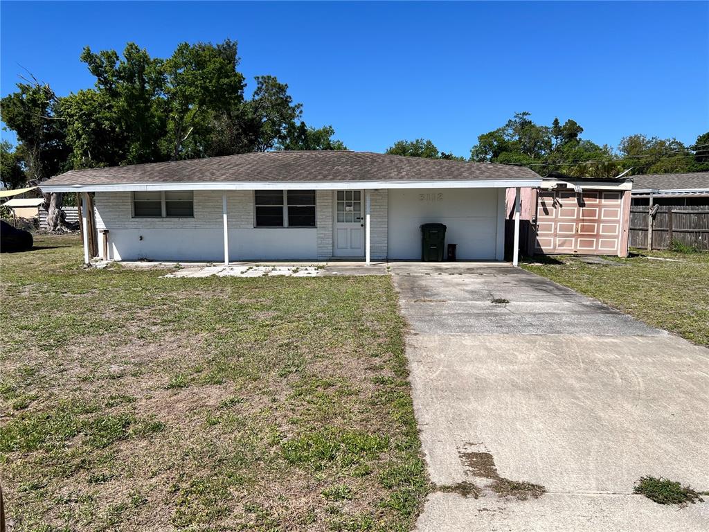 A single-story white brick house features a covered porch, a driveway, and an attached garage — 3112 SAVOY WAY, SARASOTA, FL