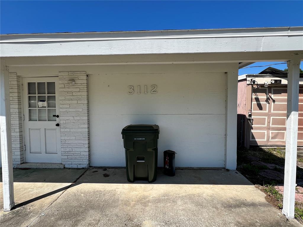 A white exterior wall features the house number 3112, a door, and a trash bin — 3112 SAVOY WAY, SARASOTA, FL