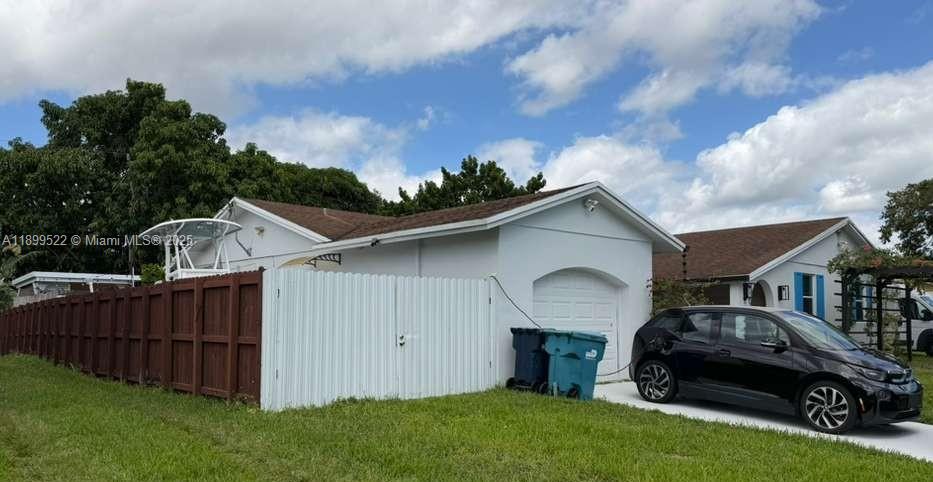 A white house with a brown roof, a wooden fence, and a black car parked outside — 10761 SW 165th St, Miami FL 33157, MIAMI, FL