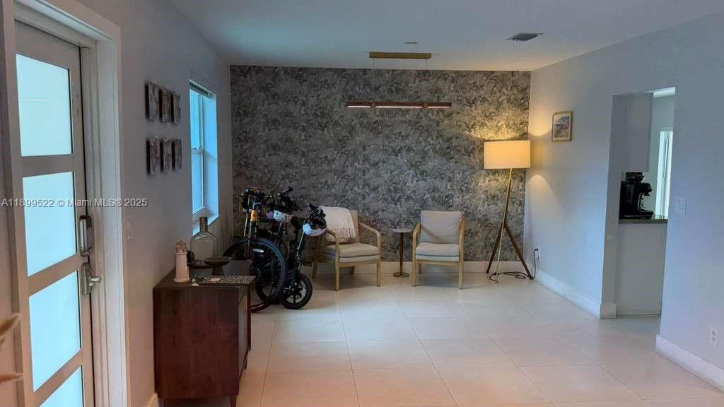This room features light tile flooring, a patterned accent wall, and two armchairs — 10761 SW 165th St, Miami FL 33157, MIAMI, FL