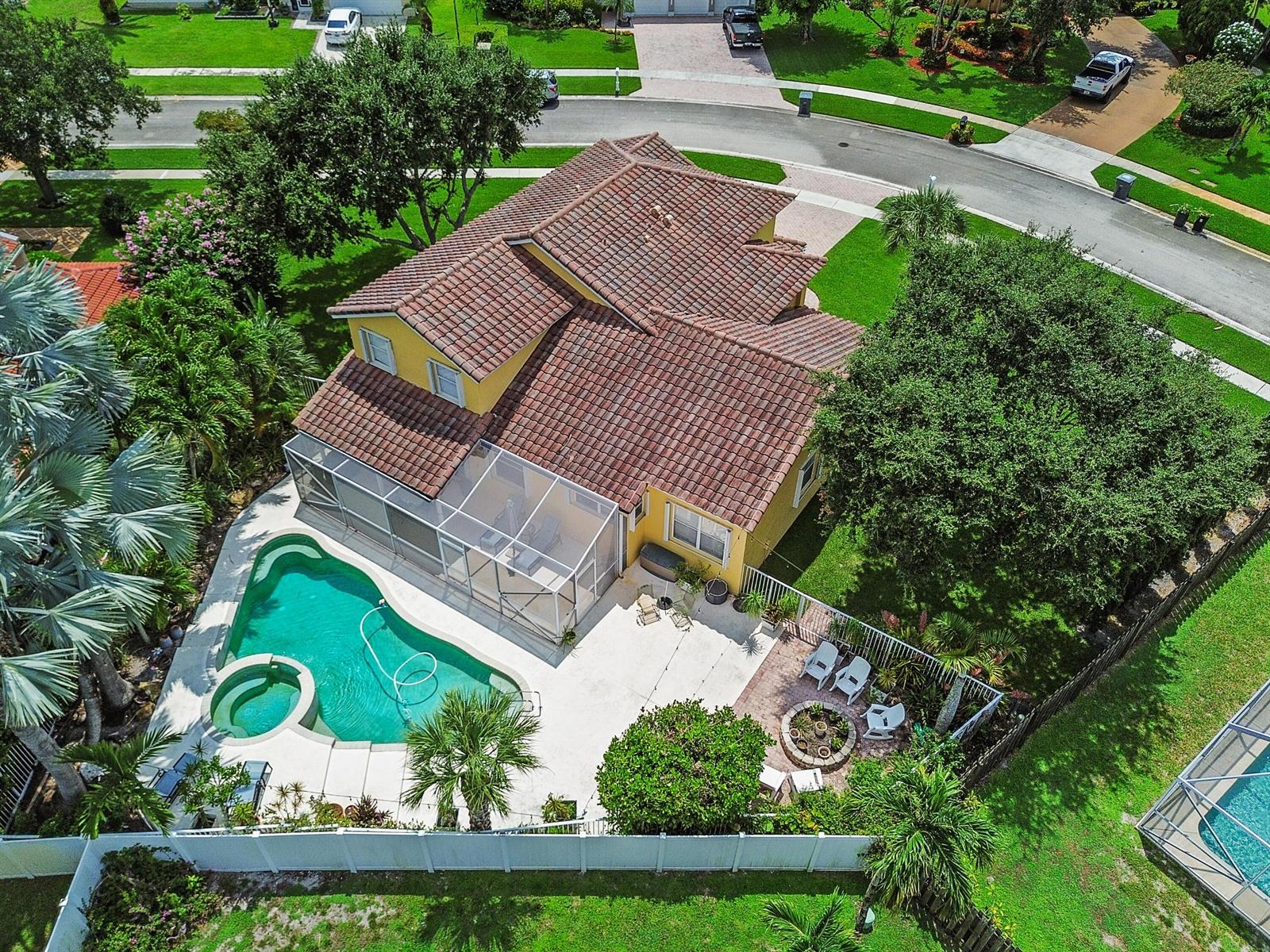 An aerial view of a yellow two-story house with a pool, spa, and patio area — 7461 Anadale Circle, Lake Worth FL 33467, LAKE WORTH, FL