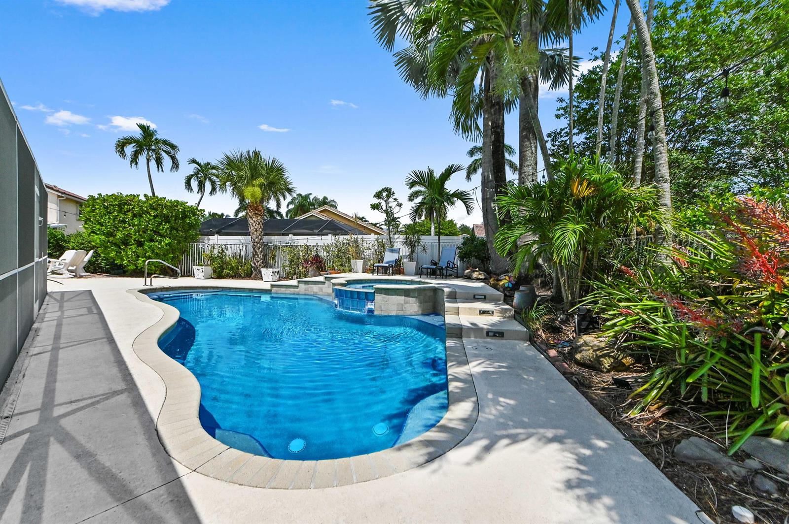 A backyard swimming pool with an attached spa, surrounded by palm trees and landscaping — 7461 Anadale Circle, Lake Worth FL 33467, LAKE WORTH, FL