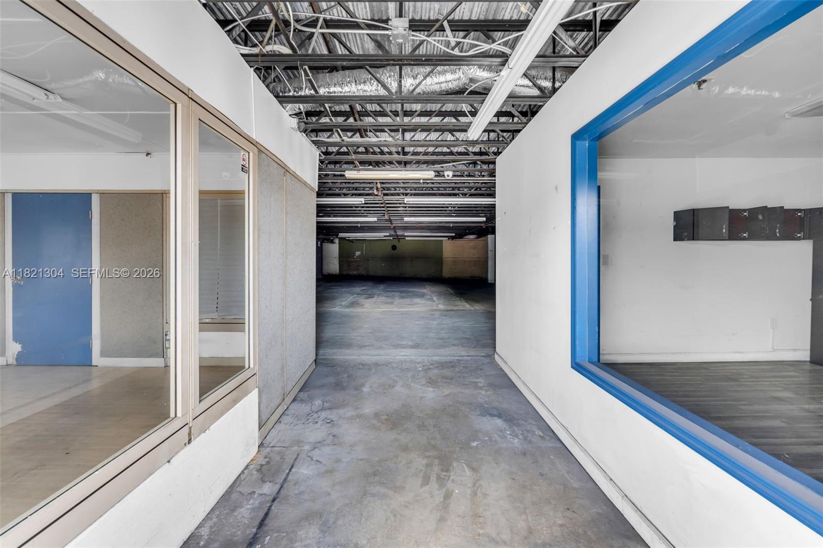 A hallway leads to an open industrial space with exposed ceiling trusses and concrete floors — 7361 NW 78th St, Medley FL 33166, MEDLEY, FL