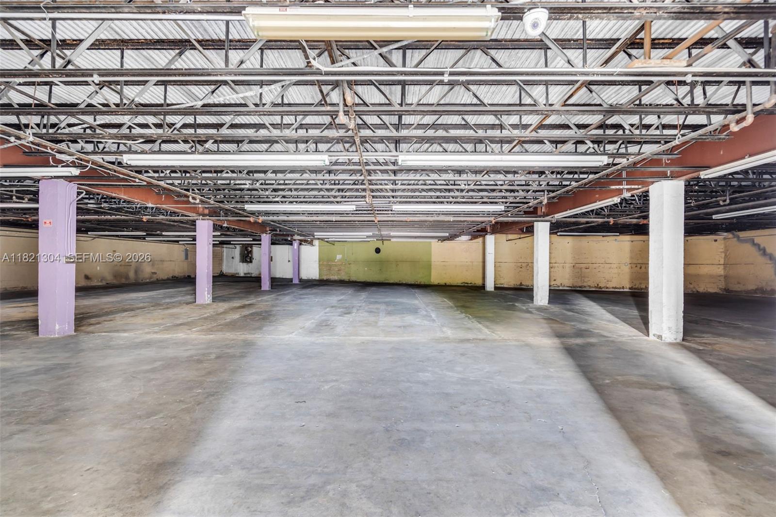 A large, empty industrial warehouse space features exposed ceiling trusses, concrete floors, and support columns — 7361 NW 78th St, Medley FL 33166, MEDLEY, FL