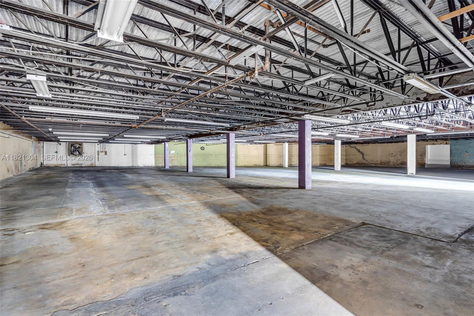An empty industrial warehouse space features exposed ceiling trusses, concrete floors, and support columns — 7361 NW 78th St, Medley FL 33166, MEDLEY, FL