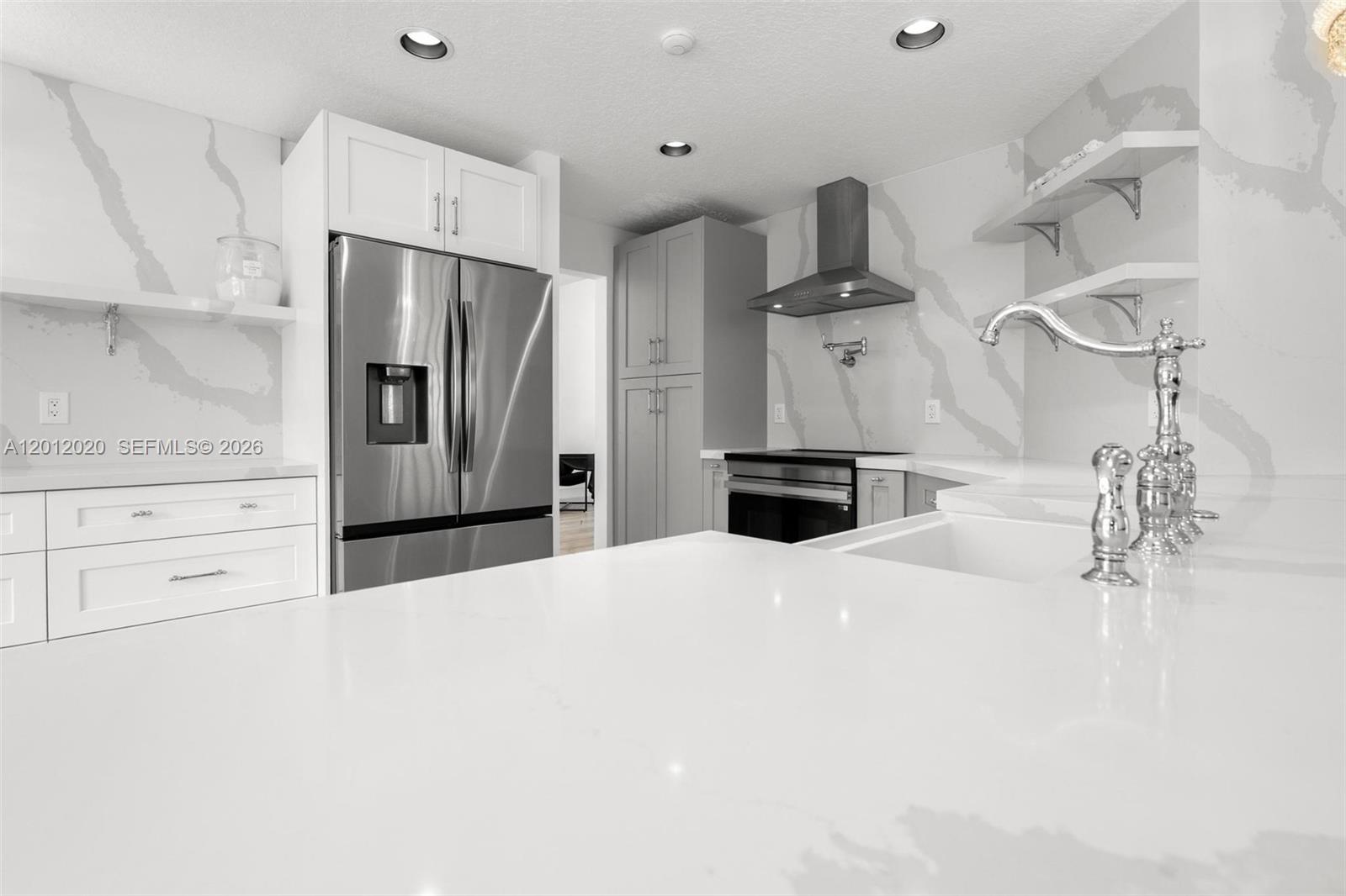 A modern kitchen features white marble-style countertops, stainless steel appliances, and white cabinetry — 303 Bridgeton Rd, Weston FL 33326, WESTON, FL