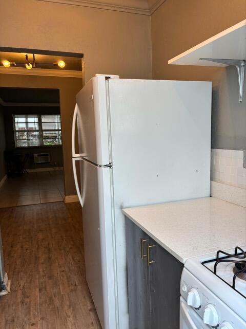 A white refrigerator stands in a kitchen next to a stove and wood-look flooring — MIAMI BEACH, FL