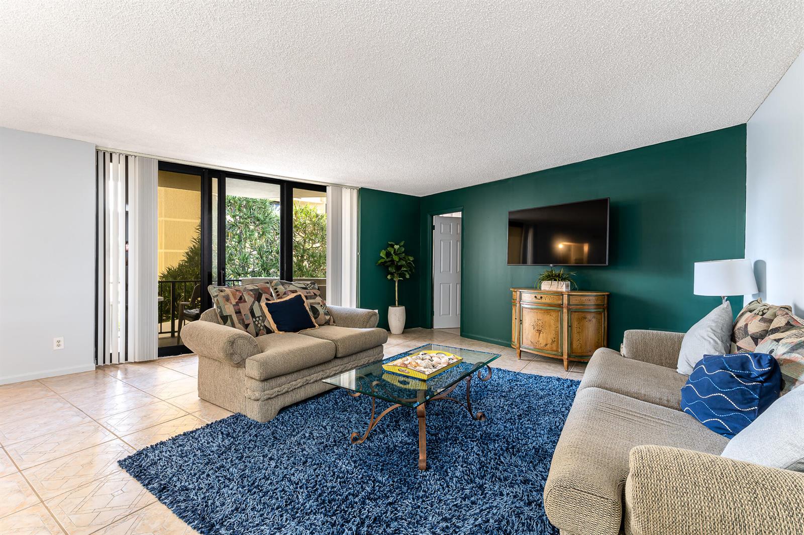 A living room features a dark green accent wall, blue shag rug, and glass coffee table — 2800 N Ocean Drive # 2b, Singer Island FL 33404, SINGER ISLAND, FL