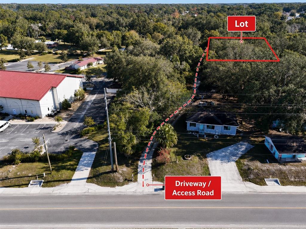 An aerial view shows a wooded lot accessible by a long driveway from the road — ORANGE STREET, LADY LAKE, FL
