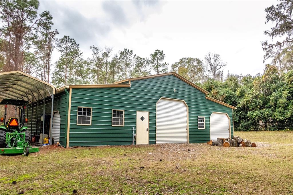 A green metal workshop building with a side carport and a tractor parked outside — 24091 RICHBARN ROAD, BROOKSVILLE, FL