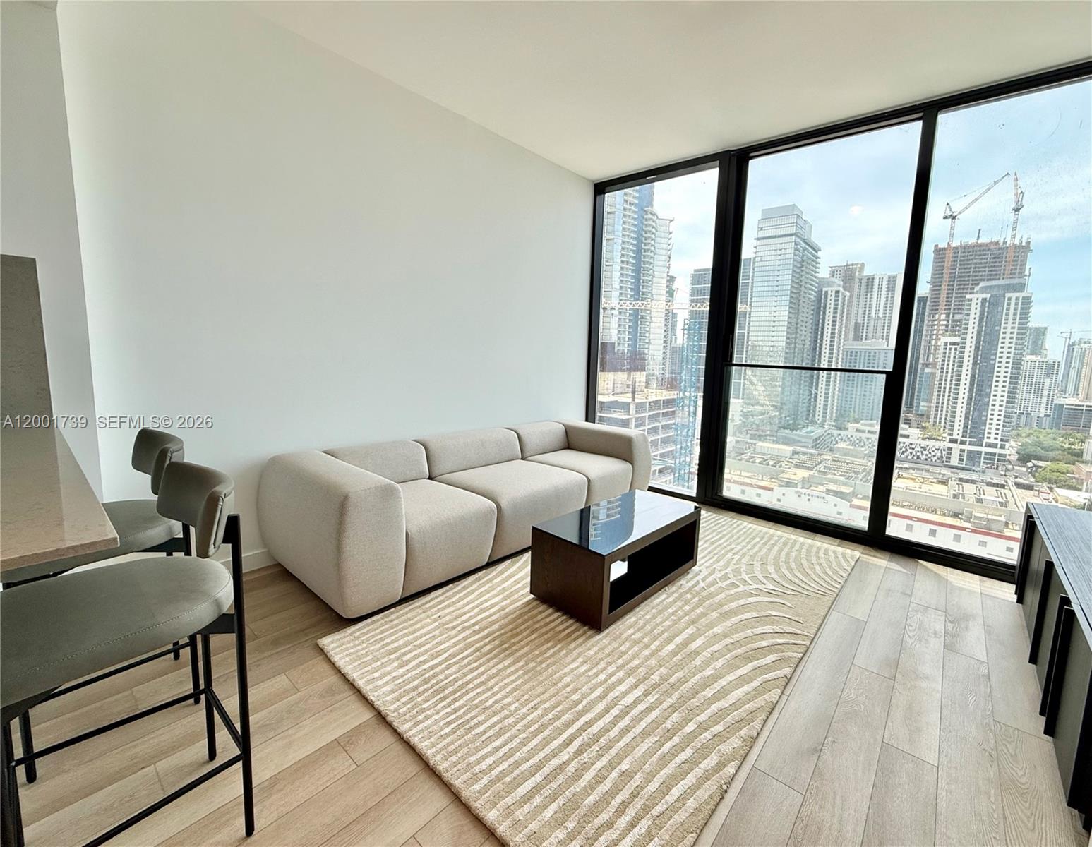 A modern living room features a beige sofa, coffee table, and floor-to-ceiling city views — 20 NE 11th St # 2809, Miami FL 33132, MIAMI, FL