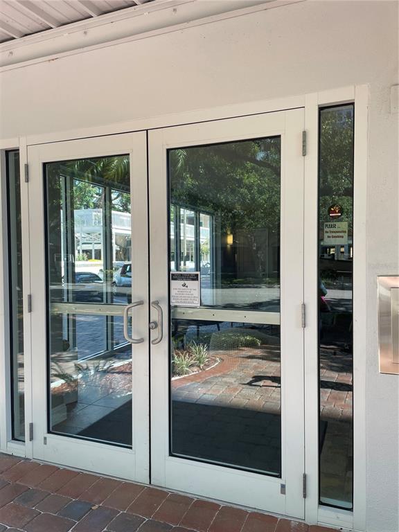 A set of double glass entry doors with white frames and a side window panel — 210 5TH AVENUE S UNIT 209, ST PETERSBURG, FL