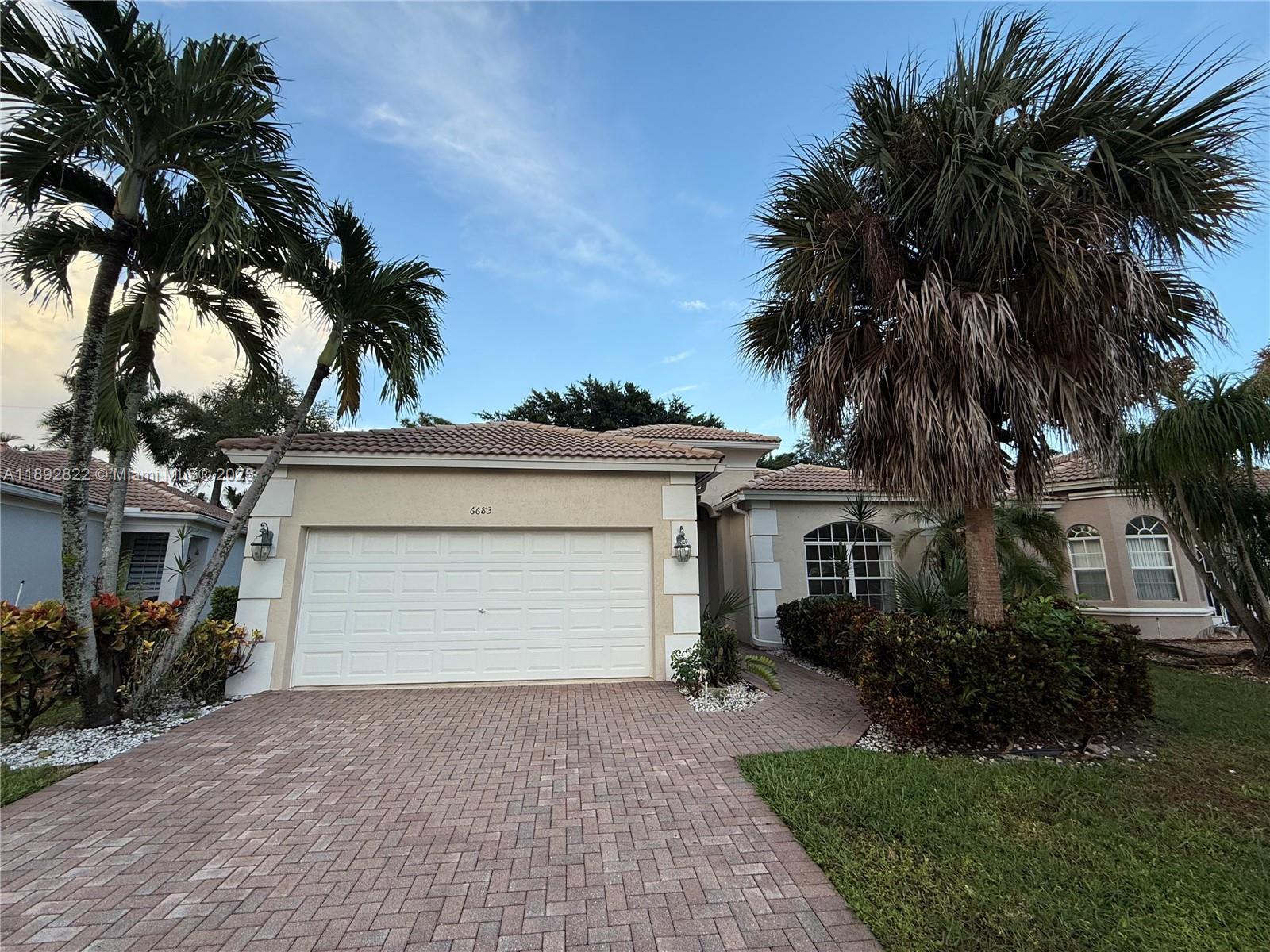 A single-story house with a paved driveway, a two-car garage, and several palm trees — 6683 Southport Dr, Boynton Beach FL 33472, BOYNTON BEACH, FL