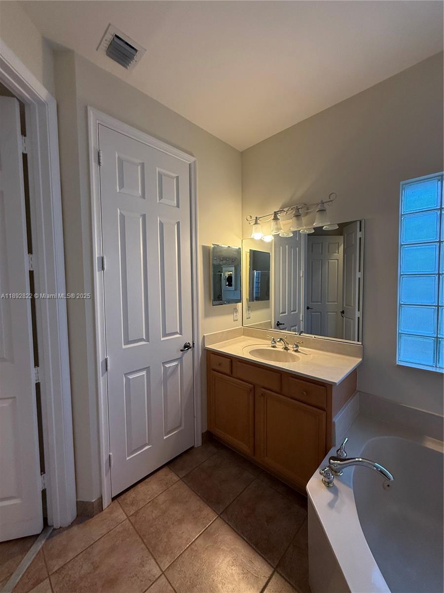 A bathroom features a wooden vanity, a large mirror, a soaking tub, and tile flooring — 6683 Southport Dr, Boynton Beach FL 33472, BOYNTON BEACH, FL