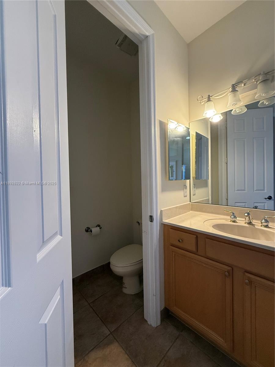 A bathroom features a wooden vanity with a sink and an adjacent enclosed toilet area — 6683 Southport Dr, Boynton Beach FL 33472, BOYNTON BEACH, FL