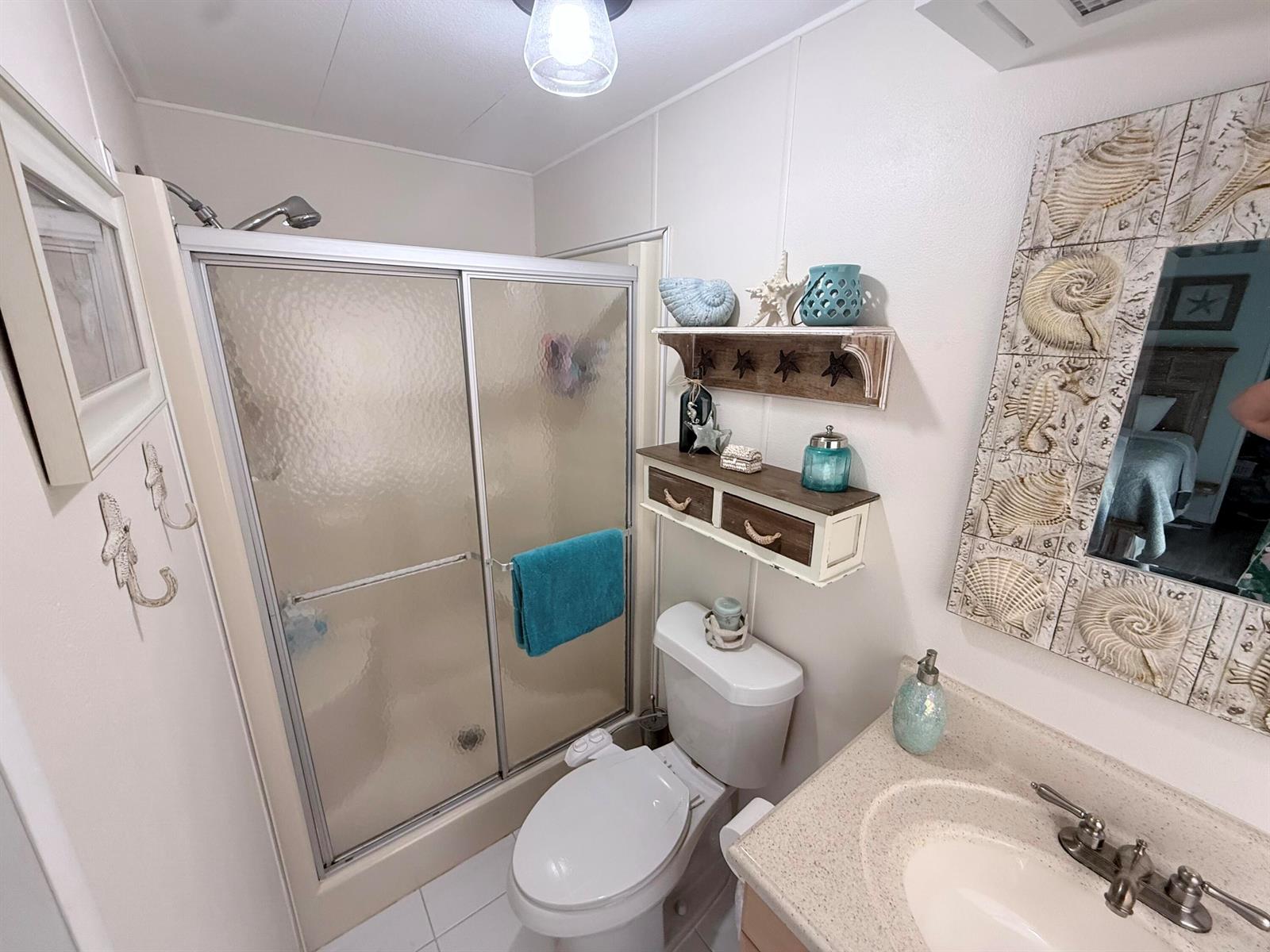A bathroom features a glass-enclosed shower, a toilet with a bidet attachment, and coastal decor — 225 W 2nd Court, Key Largo FL 33037, KEY LARGO, FL