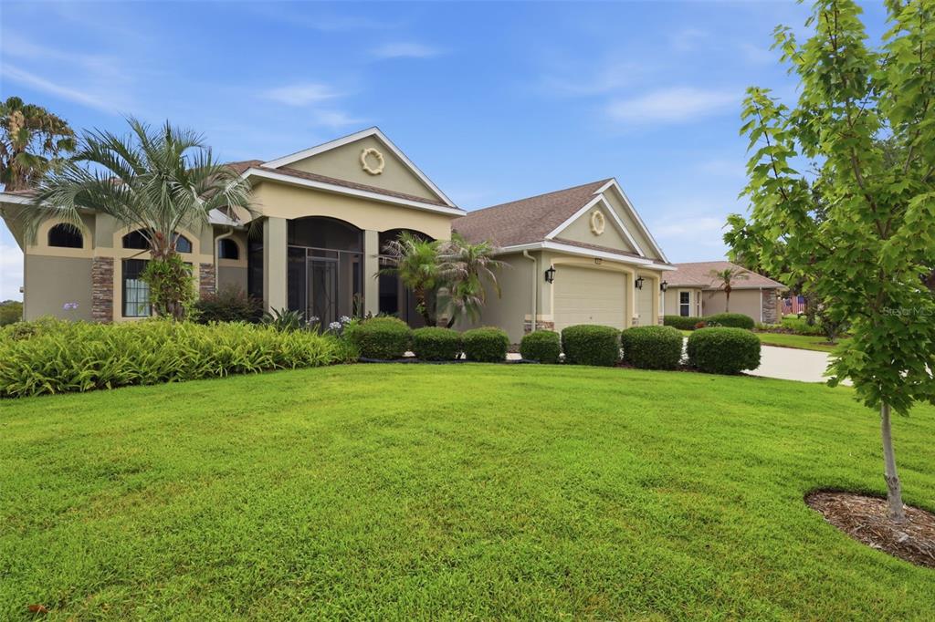A single-story house with a tan stucco exterior, a screened entryway, and a two-car garage — 7879 CROSSWINDS WAY, MOUNT DORA, FL