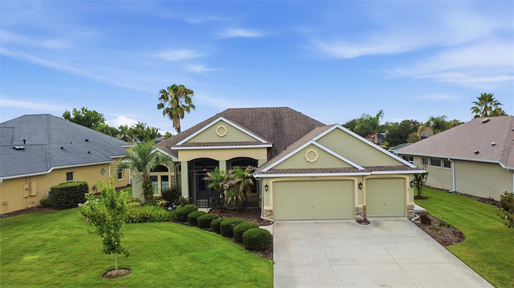 An exterior view of a single-story house with a green facade and a concrete driveway — 7879 CROSSWINDS WAY, MOUNT DORA, FL