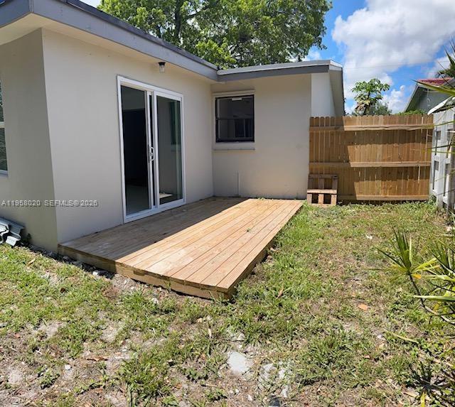 A wooden deck sits outside a house with a sliding glass door and a fence — 3840 NE 12th Ave, Pompano Beach FL 33064, POMPANO BEACH, FL