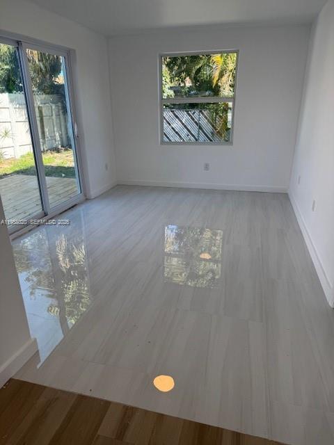 A bright, empty room features light-colored tile flooring, white walls, and a sliding glass door — 3840 NE 12th Ave, Pompano Beach FL 33064, POMPANO BEACH, FL