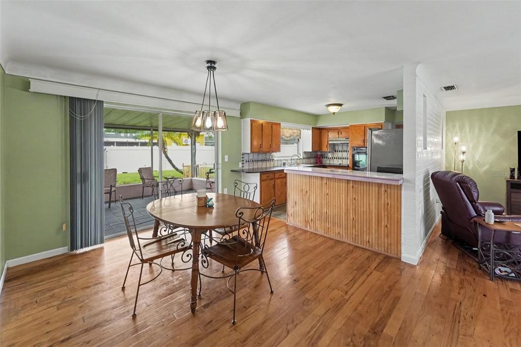 A dining area with a wooden table and chairs next to a kitchen with wood cabinets — 6026 44TH AVENUE N, KENNETH CITY, FL