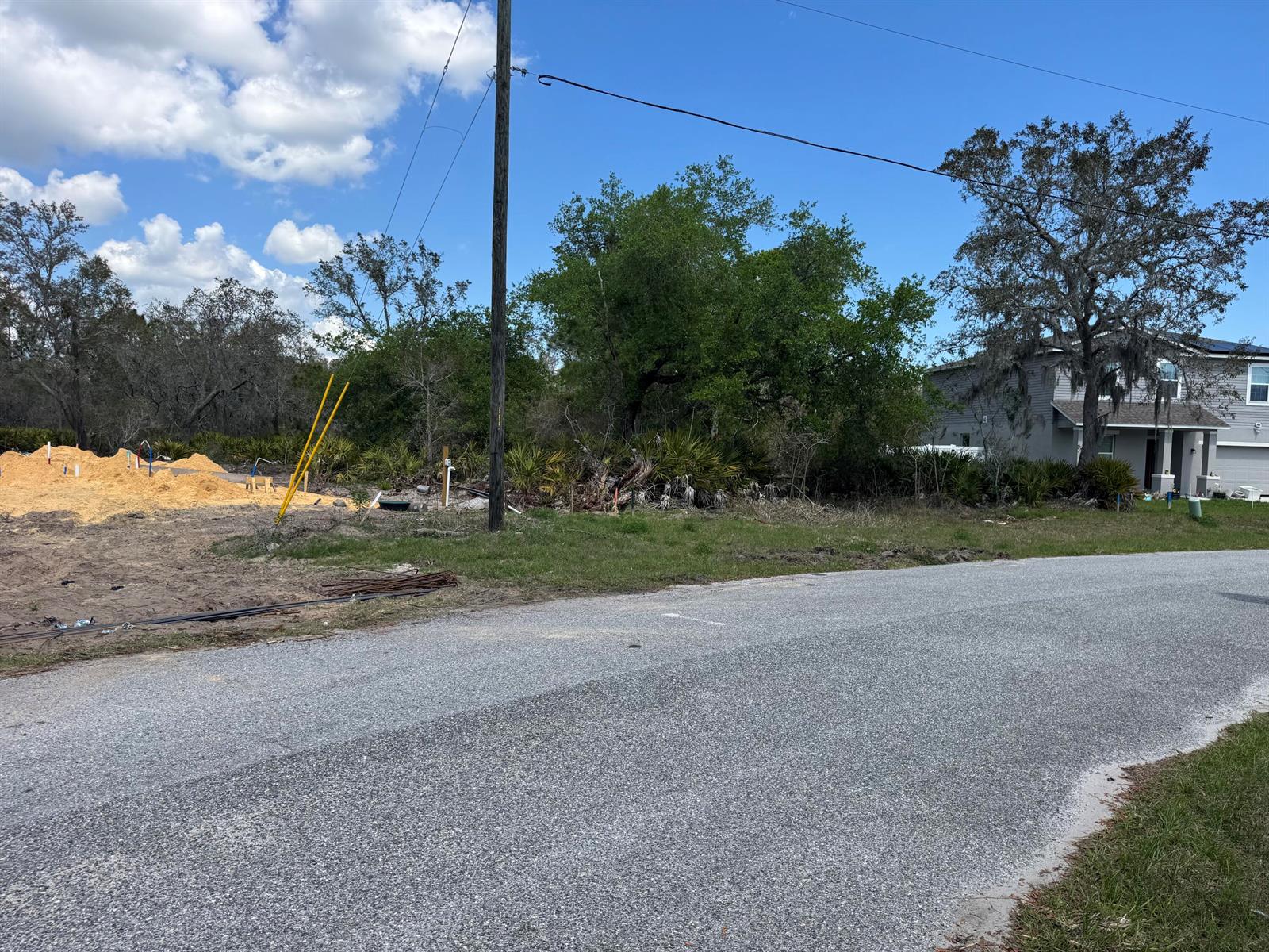 A vacant lot with a sand pile and utility pipes sits next to a suburban house — 1625 Pickerel Court, FL 34759, FL