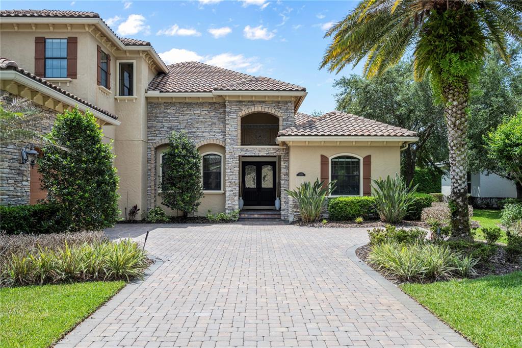 A two-story stucco and stone house with a paved driveway and a palm tree — 11753 VINCI DRIVE, WINDERMERE, FL