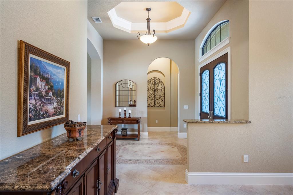 A tiled entryway features a tray ceiling, arched doorway, and a dark wood console table — 11753 VINCI DRIVE, WINDERMERE, FL