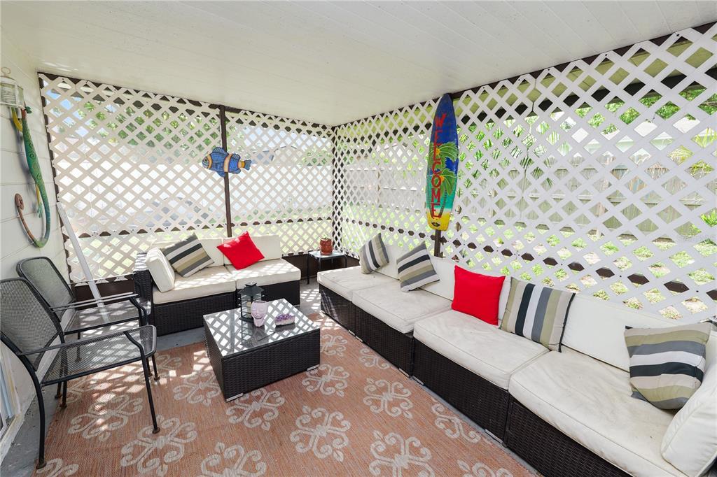 A covered patio features wicker furniture, a patterned rug, and white lattice walls — 4820 PRESIDENTIAL STREET, SEFFNER, FL