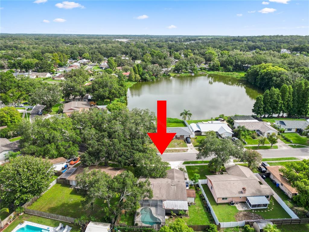 An aerial view shows a residential neighborhood with a lake and a red arrow pointing down — 4820 PRESIDENTIAL STREET, SEFFNER, FL