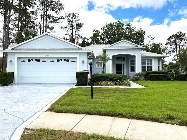 A light blue single-story house features a two-car garage and a landscaped front yard — 11752 WAYSIDE WILLOW COURT, HUDSON, FL